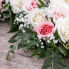 Elegant bouquet with pink and white roses, baby's breath, and lush green foliage on a textured surface.