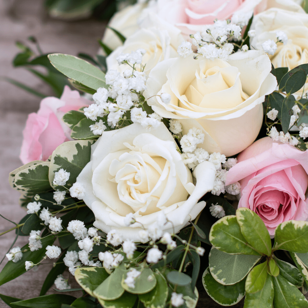 Close-up of a beautiful bouquet featuring white and pink roses with lush greenery and delicate baby's breath.