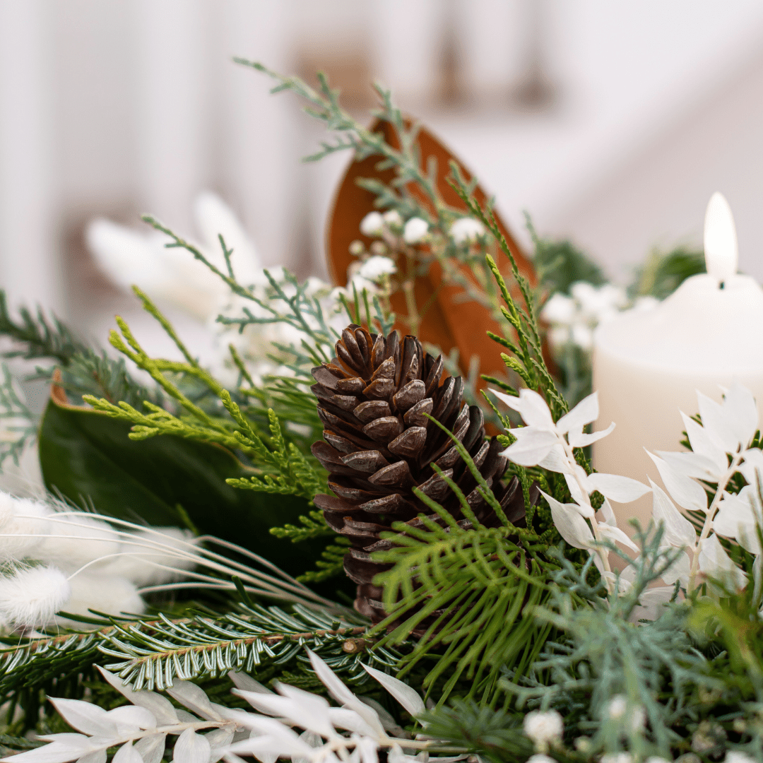 Festive pine cone and greenery centerpiece with candle, perfect for holiday decor and table arrangements.
