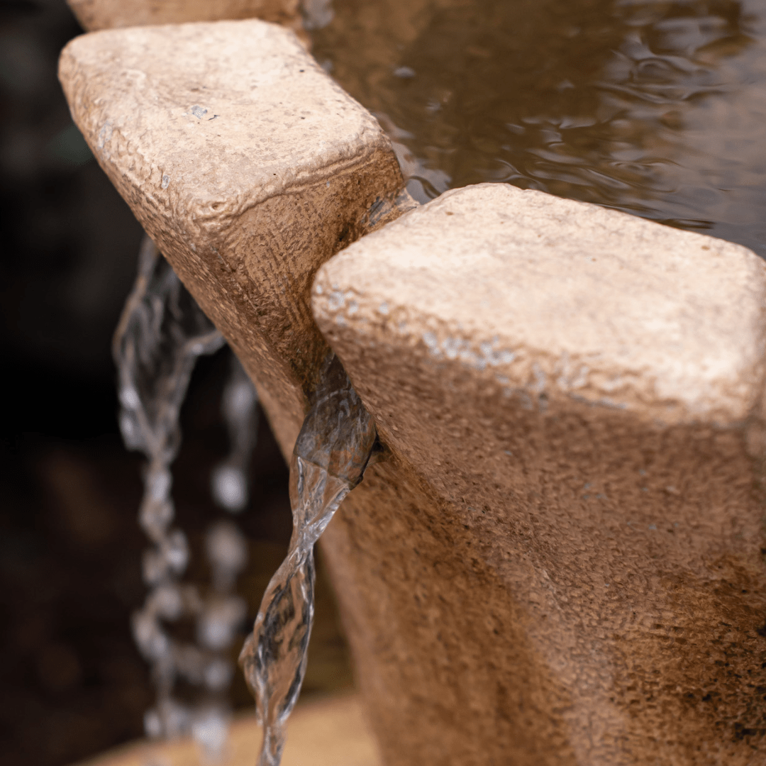 Close-up of a stone water feature with flowing water creating a soothing, natural ambiance.