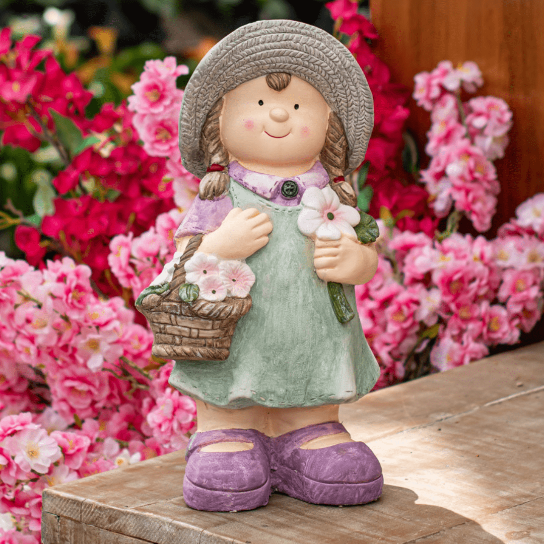 A cute garden statue of a girl with a basket of flowers, surrounded by vibrant pink blooms.