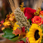 Vibrant autumn bouquet with red roses, sunflowers, and fall leaves, perfect for seasonal decor or festive occasions.