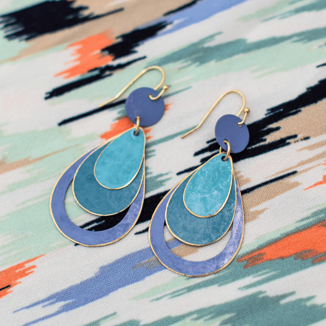 Colorful boho earrings with layered blue teardrop design on a vibrant abstract fabric background.
