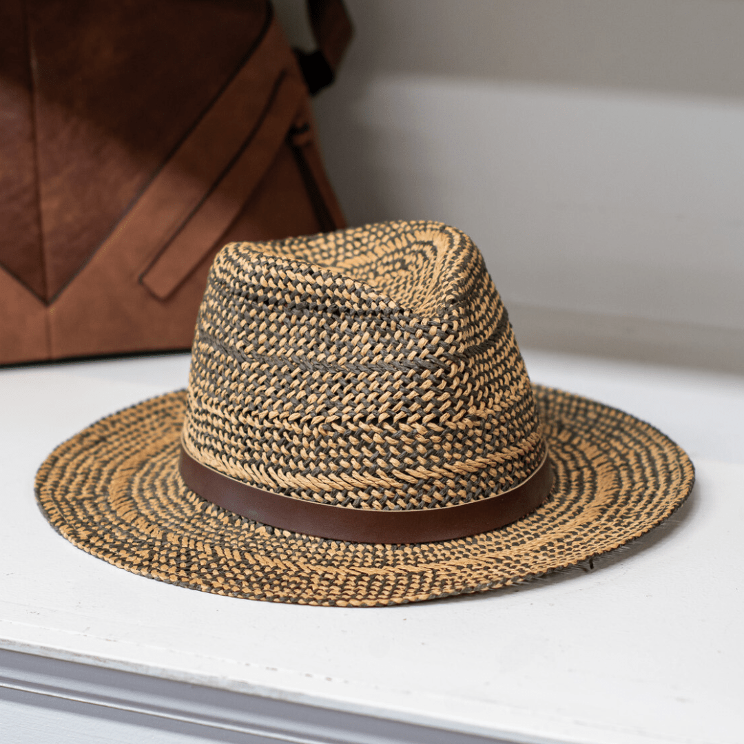 Stylish straw fedora with brown band on a white shelf, ideal for summer fashion accessory.