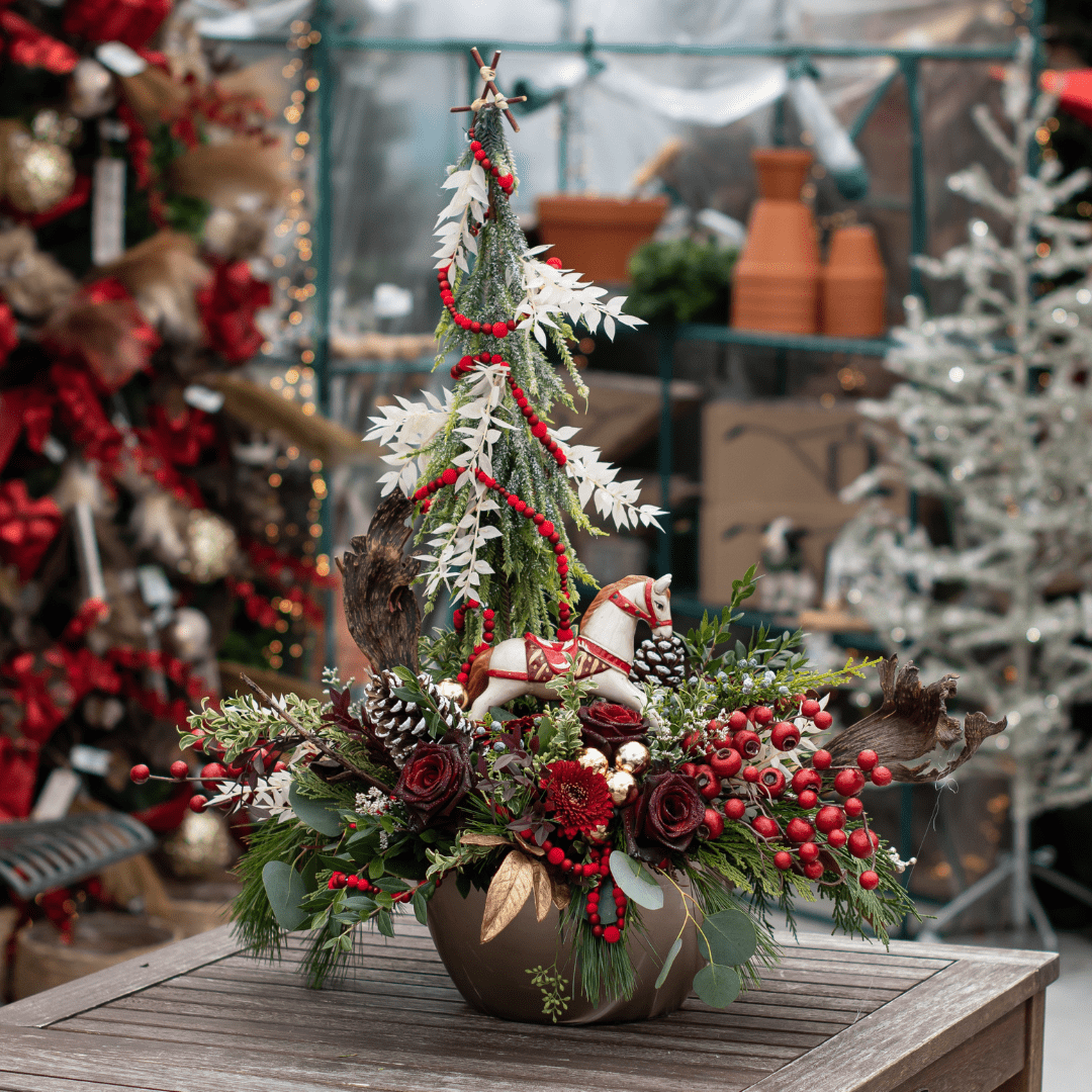 Design of the Day 2022 (6) Festive Christmas floral arrangement with red accents, pinecones, and a decorative horse, perfect for holiday décor.