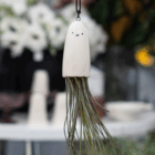 Cute ghost-shaped ceramic air plant holder hanging indoors.
