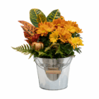 Autumn flower arrangement with orange chrysanthemums and foliage in a metal bucket.