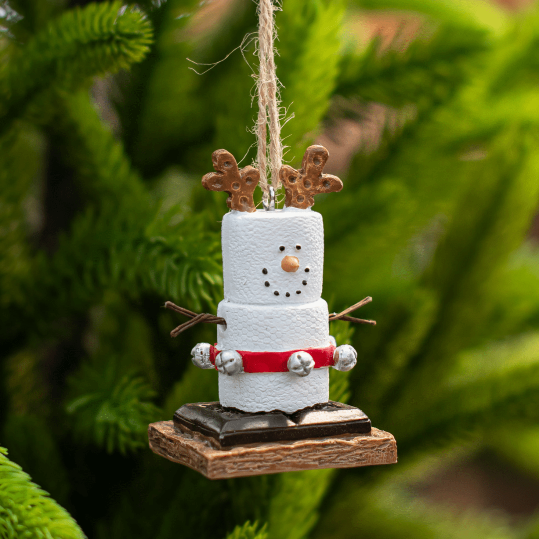 Homemade snowman ornament with pretzel antlers and festive decor on a green Christmas tree.
