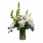 Elegant white floral arrangement in a clear vase with lush green foliage, perfect for weddings or celebrations.