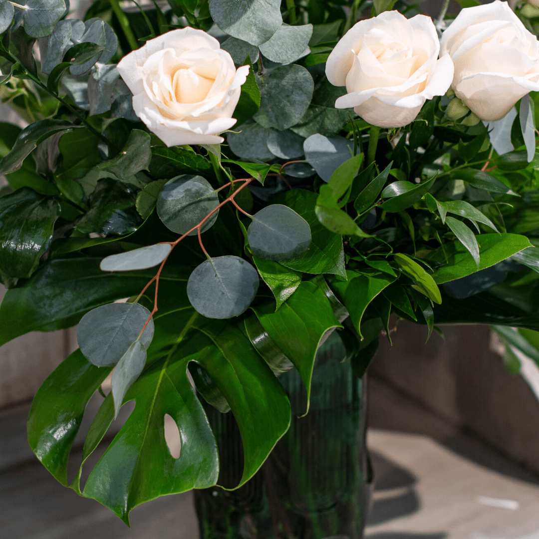 Elegant bouquet with white roses and lush green leaves, perfect for wedding or home decor.