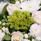 Elegant white roses and chrysanthemums with lush greenery create a stunning floral arrangement.