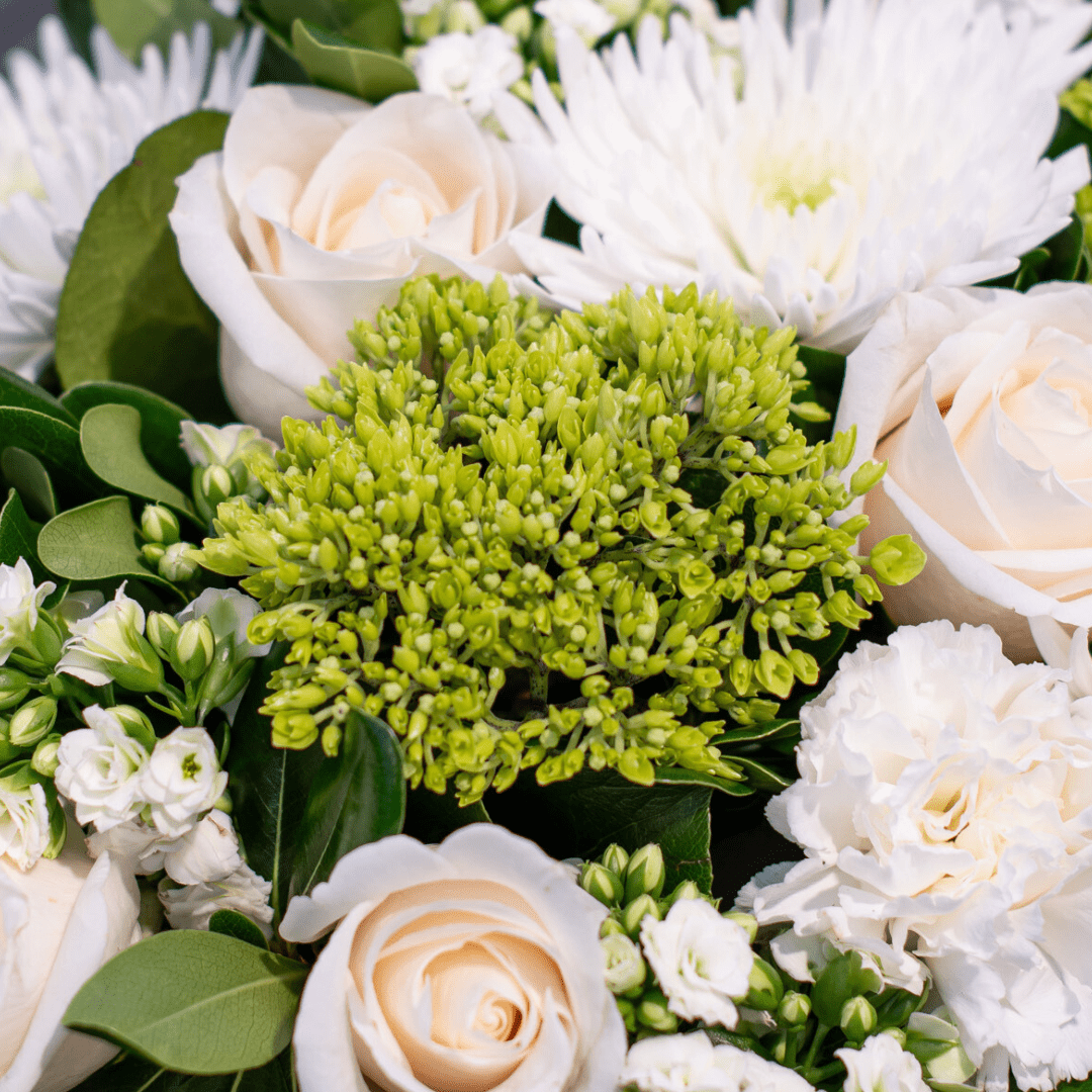 Elegant white roses and chrysanthemums with lush greenery create a stunning floral arrangement.