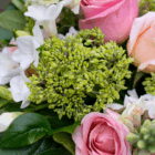 Close-up of a vibrant flower bouquet with pink roses, white blossoms, and lush green leaves for a fresh, floral look.