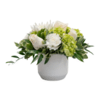Elegant white and green floral arrangement in a white vase, featuring roses, hydrangeas, and lush greenery.