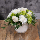 Elegant white rose and chrysanthemum bouquet in a ceramic vase on a wooden table.