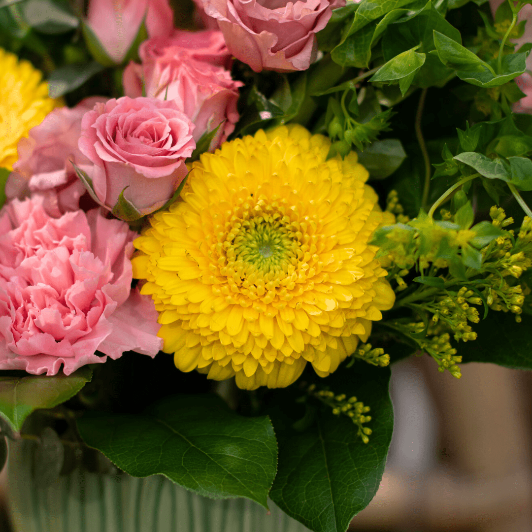 Vibrant bouquet with pink roses, yellow gerbera daisy, and green foliage. Perfect for a cheerful floral arrangement.