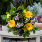 Vibrant floral bouquet with yellow gerberas and lavender roses, perfect for gifts or decor in a flower shop setting.