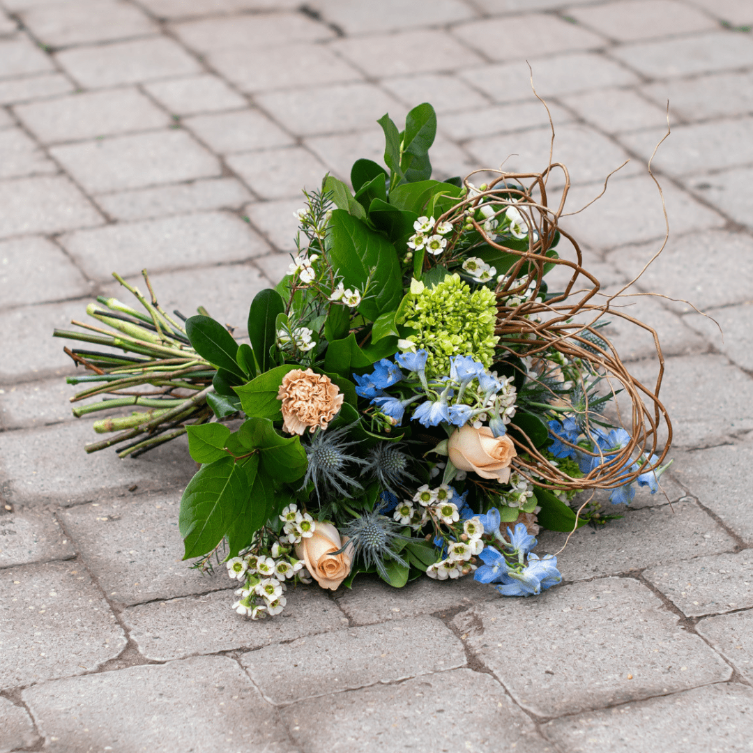 Wildflower bouquet with roses and greenery on cobblestone. Organic, rustic floral arrangement for weddings or events.