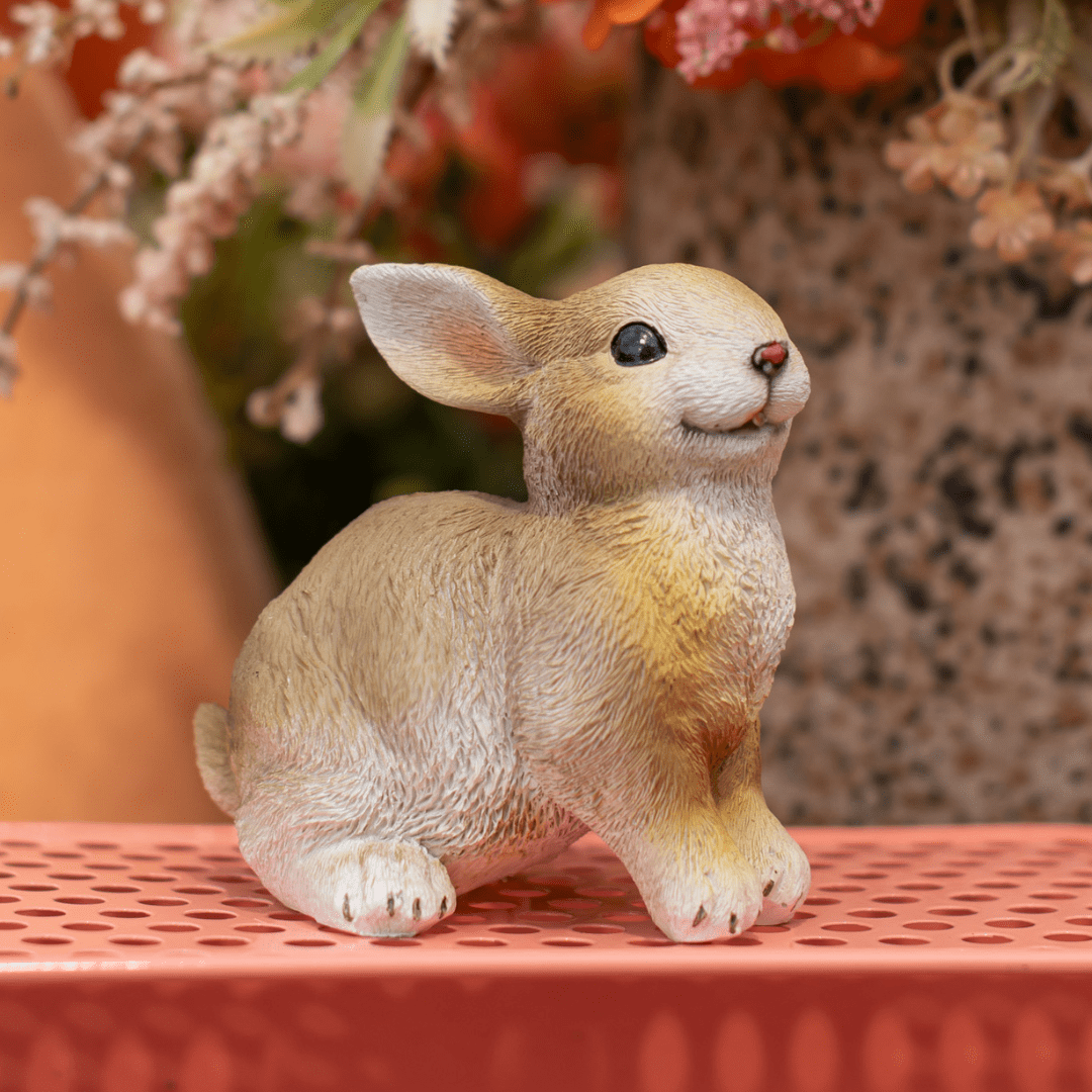 Cute bunny figurine on a pink surface with floral background decor, perfect for a cheerful home display.