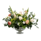 A floral arrangement with white roses, peonies, snapdragons, and lisianthus, peach-coloured ranunculus, and lime green hydrangeas arranged in a glass pedestal.