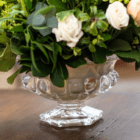 A close-up of a glass pedestal as part of a floral arrangement.