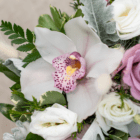 A close-up of a white phalaenopsis orchid in a floral arrangement.