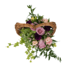 A view from above of a floral arrangement with pink and purple roses, lisianthus, and dianthus, as well as variegated ivy, arranged in a wicker heart-shaped basket.