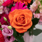 A close-up of a bold orange rose in a fresh floral arrangement!