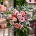 An image of an all-pink bouquet of roses and peonies with silvery dusty miller and eucalyptus stems.