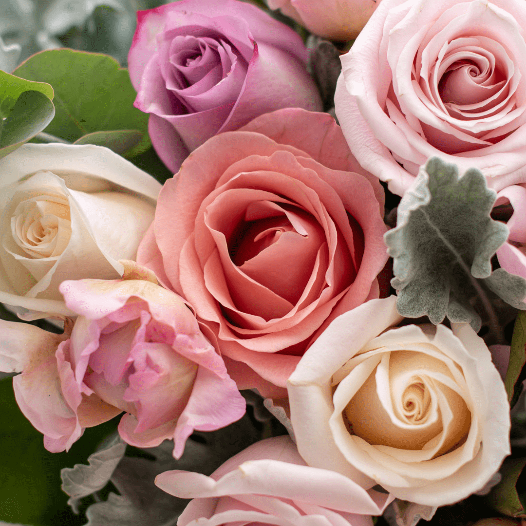 A close-up of a peach rose in a fresh floral arrangement.