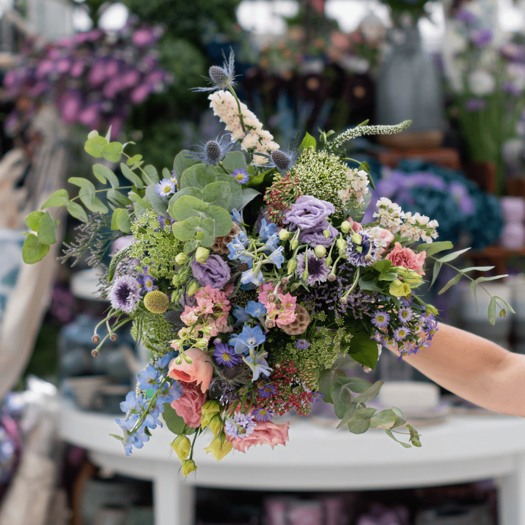 An image of a wildflower bouquet with stems of purple, pink, light blue, and yellow cut flowers.
