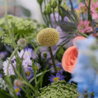 A close-up of a small yellow globe-shaped flower in a wildflower bouquet.