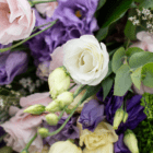A close-up of white lisianthus blooms in a fresh floral arrangement with other pale pink and purple flowers.