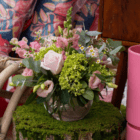 A pink and lime green floral arrangement in a clear glass round vase.