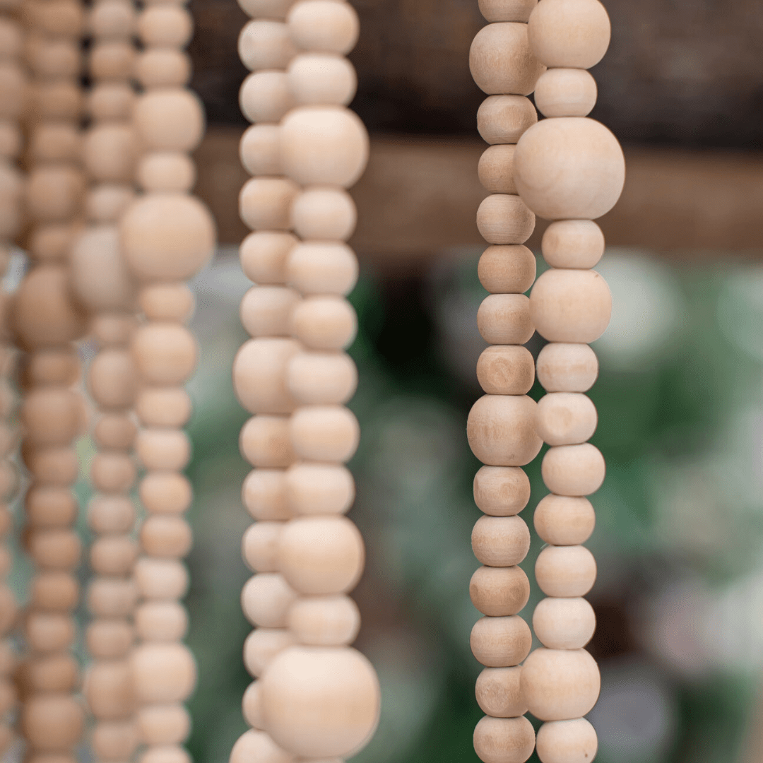 Strands of wooden beaded garland hangs from a display.