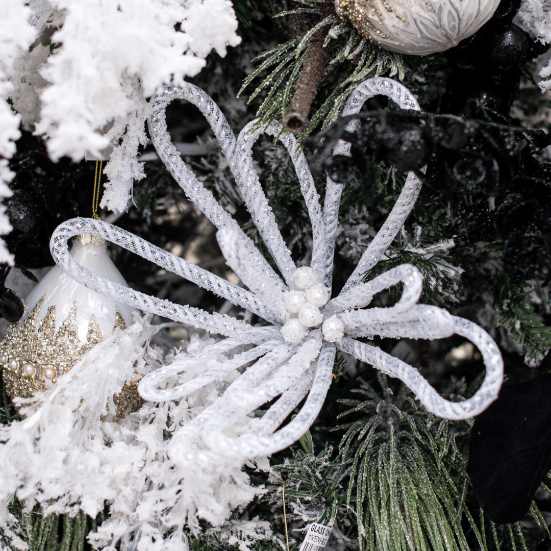 A wiry white faux flower pick in a snow-flocked artificial Christmas tree.