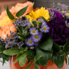 A close-up of small purple asters with yellow centers in a fresh floral arrangement.
