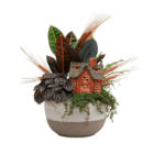 A fall-themed indoor mixed planter in a brown and cream ombre pot with a colourful croton, dark purple-black peperomia, trailing green baby tears, as well as decorative light brown wheat stems and an orange and brown brick-style ceramic house.