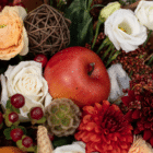 A close-up of an artificial apple in a fall floral centerpiece.