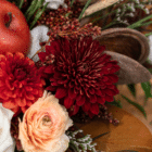 A close-up of a burnt orange dahlia in a fall floral arrangement.