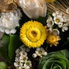 A close-up of yellow strawflower surrounded by other white cut flowers in a floral bouquet.