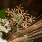 A close-up of a gold-brown artificial blossom spray in a floral bouquet.