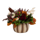A fall floral arrangement in a cream and brown striped ceramic pumpkin with white roses, burgundy carnations, magnolia leaves, etc.