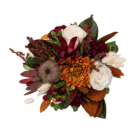 An above view of a fall floral arrangement in a cream and brown striped ceramic pumpkin with white roses, burgundy carnations, magnolia leaves, etc.