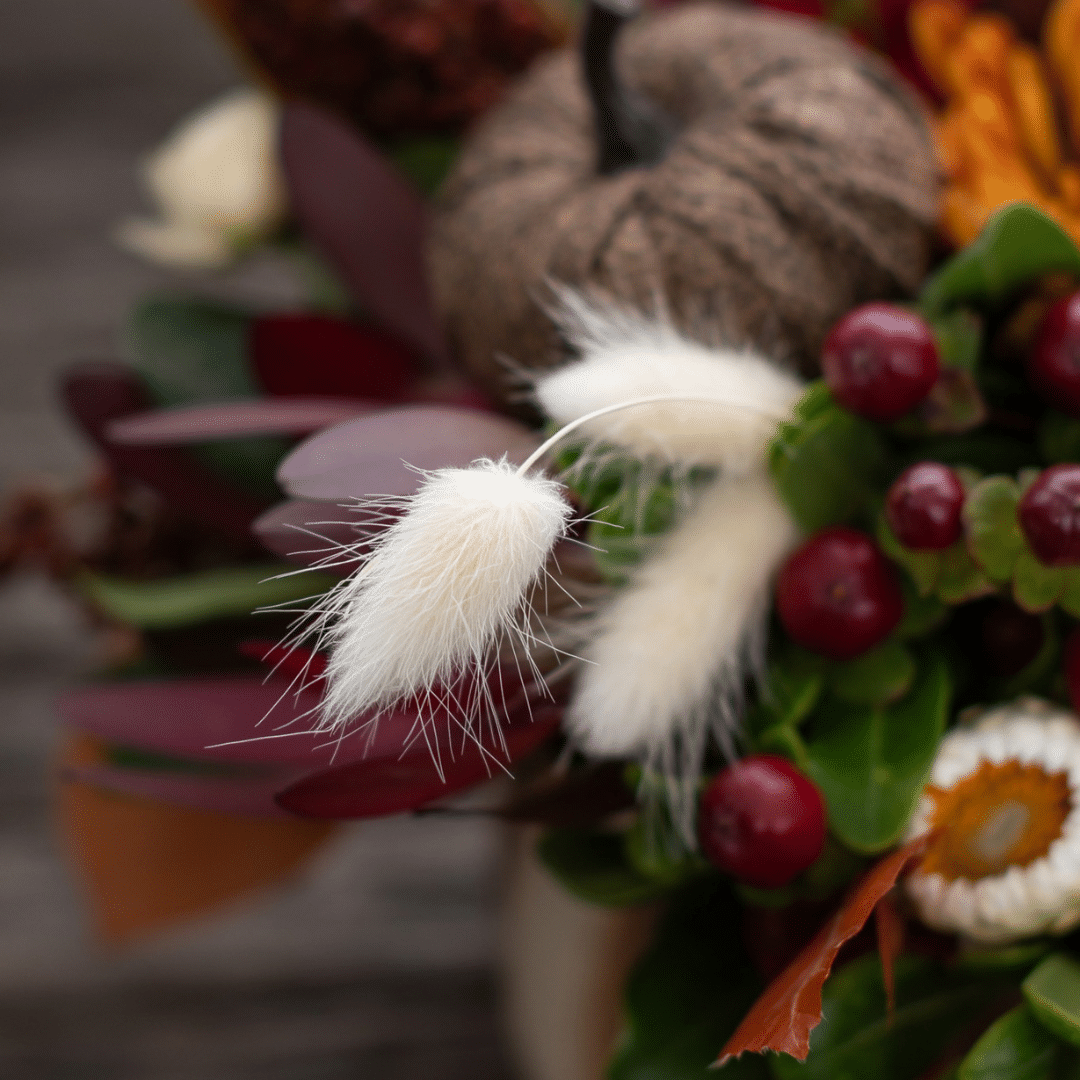 A close-up of a fluffy white bunny tail in a fall floral arrangement.