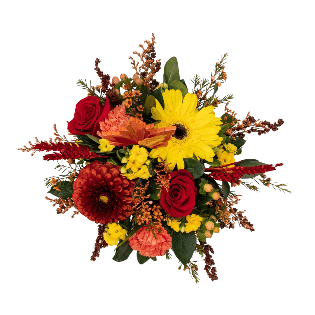 An above view of a fall floral arrangement in a white ceramic pumpkin with burnt-orange dahlias, peach carnations, yellow kalanchoes, etc.