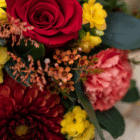 A close-up of orange wax flower in a fall floral arrangement.