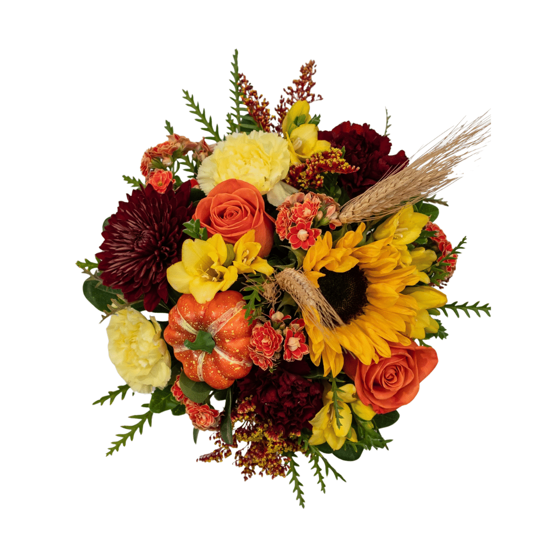 An above view of a floral arrangement in an orange ceramic pumpkin with sunflowers, yellow freesia, orange roses, etc.