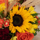 A close-up of a yellow sunflower in a fall floral arrangement.