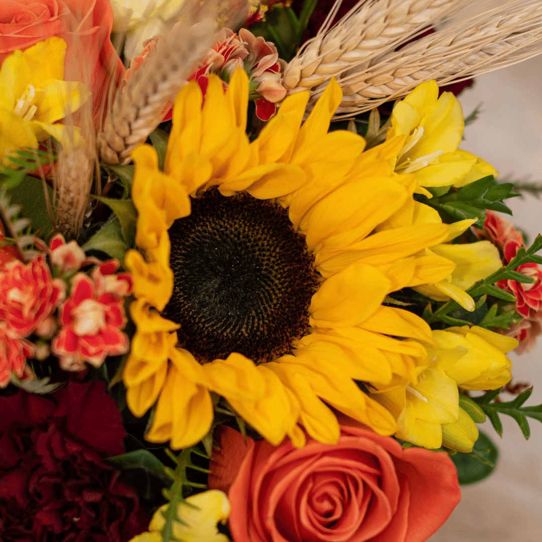 A close-up of a yellow sunflower in a fall floral arrangement.